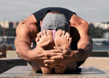 Athlete performing a seated forward fold to stretch the hamstrings and release the lower back.